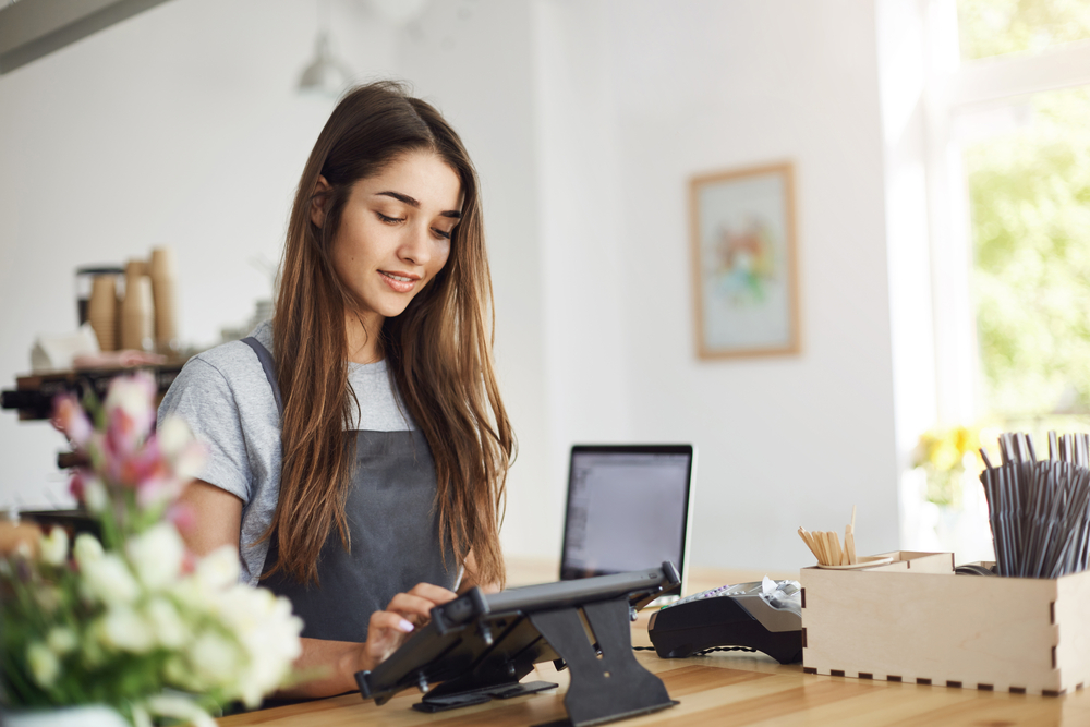 young female barista running a cafe using the payment terminal