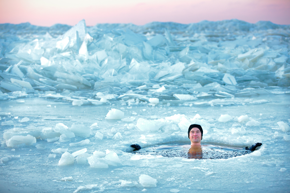 氷の張った湖に笑顔で浸かる男